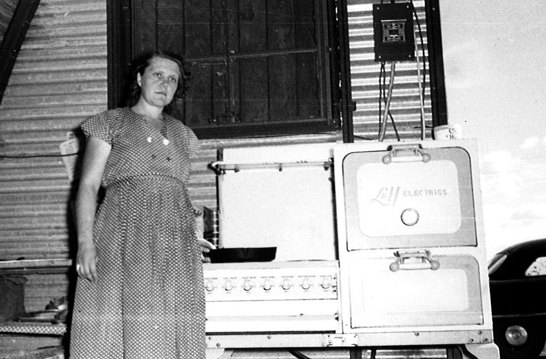 Lady standing in front of her first stove. 