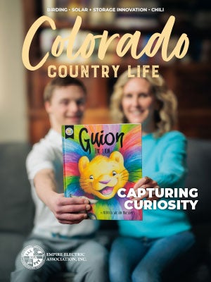 March 2025 Colorado Country Life cover photo of a couple sitting on a couch holding a book so the cover can be seen