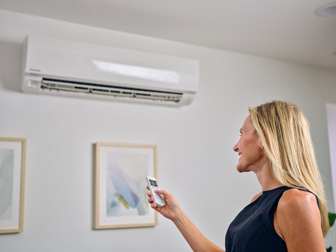 Woman changing heat pump settings using a remote